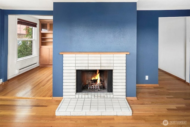 404 E Harrison St Unit 301, Seattle, WA 98102 - detailed view of baseboard heating, wood finished floors, a brick fireplace, and ornamental molding