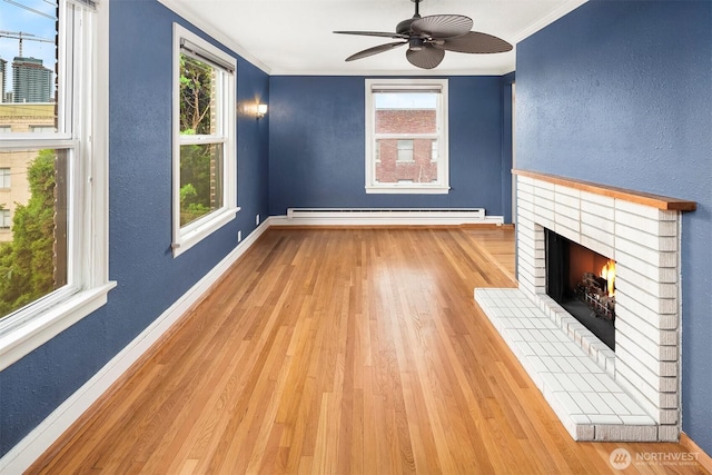 404 E Harrison St Unit 301, Seattle, WA 98102 - unfurnished living room featuring baseboard heating, crown molding, wood finished floors, a brick fireplace, and a ceiling fan