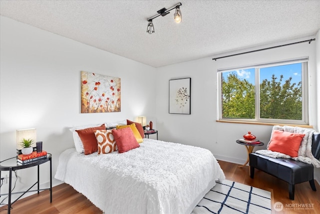 732 11th Ave E Unit 404, Seattle, WA 98102 - bedroom featuring wood finished floors, rail lighting, and a textured ceiling
