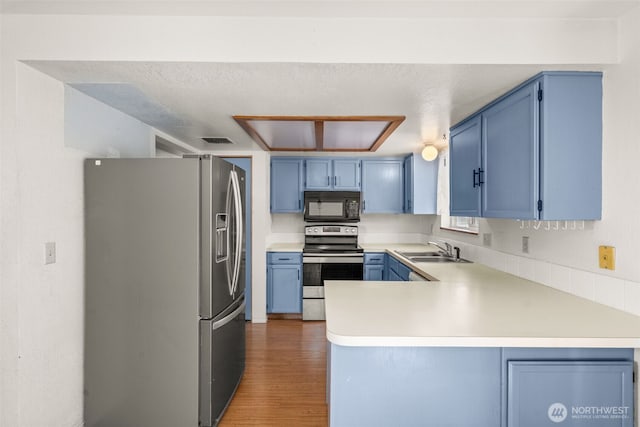 309 SW 6th St, Chehalis, WA 98532 - kitchen with appliances with stainless steel finishes, a peninsula, blue cabinetry, and light wood-style flooring