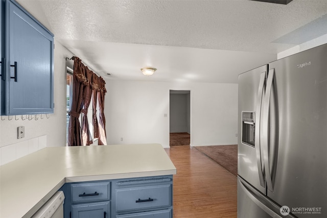 309 SW 6th St, Chehalis, WA 98532 - kitchen with stainless steel fridge, blue cabinets, open floor plan, a peninsula, and a textured ceiling