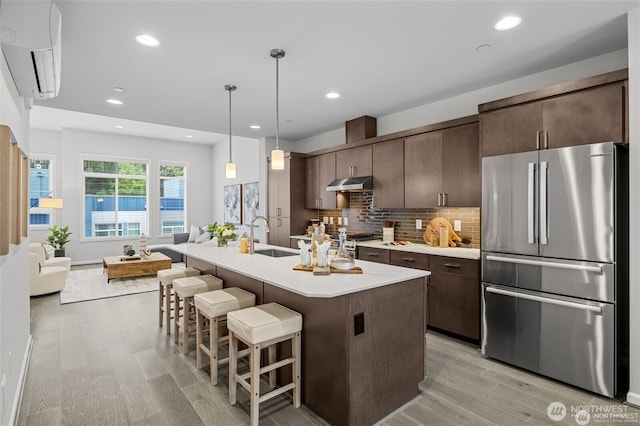 7629 NE 122nd Ct Unit 7, Kirkland, WA 98034 - kitchen featuring freestanding refrigerator, under cabinet range hood, a wall mounted air conditioner, light wood-style flooring, and light countertops