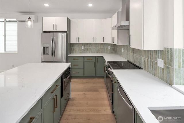 727 18th Ave, Seattle, WA 98122 - kitchen with stainless steel appliances, wall chimney exhaust hood, a wall mounted air conditioner, white cabinetry, and pendant lighting