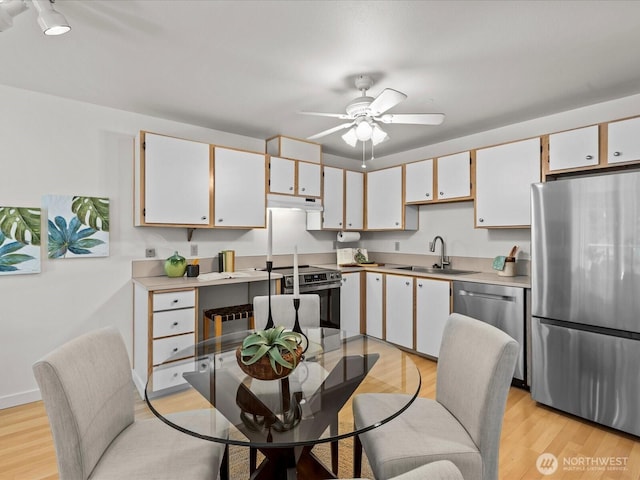 5225 50th Ave NE Unit 103, Seattle, WA 98105 - kitchen featuring stainless steel appliances, light wood-style floors, a ceiling fan, under cabinet range hood, and light countertops