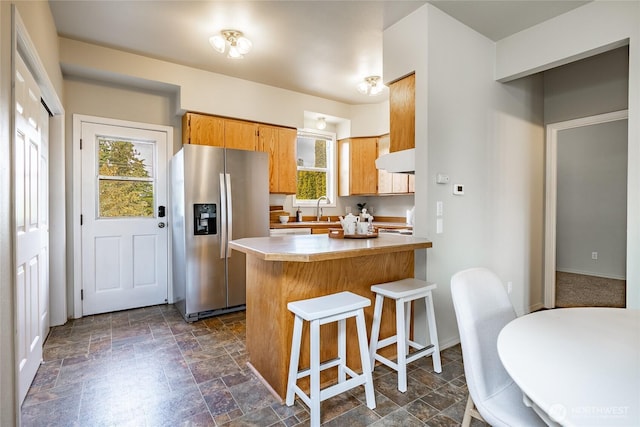 1609 Humboldt St, Bellingham, WA 98225 - kitchen with stainless steel fridge, stone finish flooring, range hood, a kitchen breakfast bar, and a peninsula