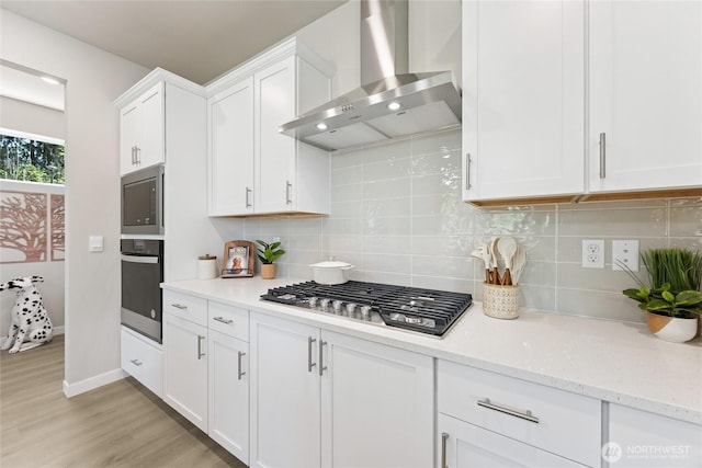 26808 NE 143rd Cir Unit 25, Duvall, WA 98019 - kitchen with appliances with stainless steel finishes, wall chimney exhaust hood, white cabinets, light wood-style flooring, and decorative backsplash