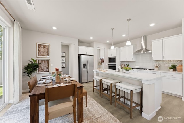 26808 NE 143rd Cir Unit 25, Duvall, WA 98019 - kitchen featuring appliances with stainless steel finishes, wall chimney exhaust hood, a kitchen breakfast bar, backsplash, and light countertops