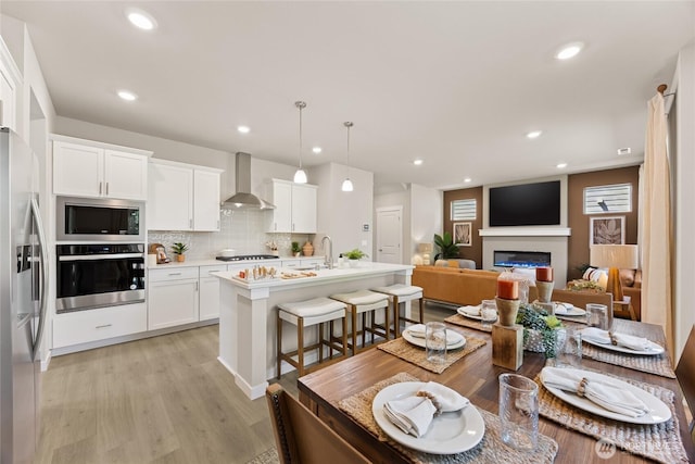 26800 NE 143rd Cir Unit 27, Duvall, WA 98019 - kitchen featuring appliances with stainless steel finishes, wall chimney range hood, backsplash, light countertops, and a breakfast bar