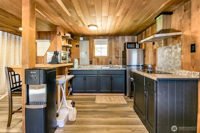 32113 Whitman Lake Dr, Graham, WA 98338 - kitchen with appliances with stainless steel finishes, exhaust hood, wooden ceiling, wood walls, and light wood-style floors