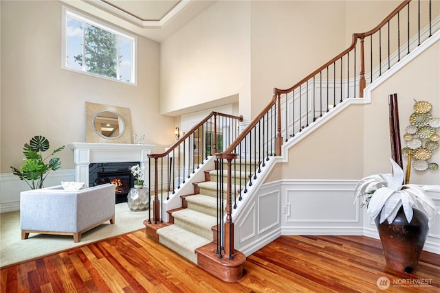 15025 SE 43rd St, Bellevue, WA 98006 - stairway featuring wood finished floors, a premium fireplace, a high ceiling, and wainscoting