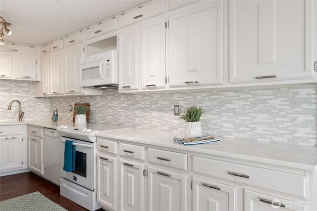 22315 6th Ave S Unit A109, Des Moines, WA 98198 - kitchen featuring white appliances, white cabinetry, light countertops, decorative backsplash, and dark wood-type flooring