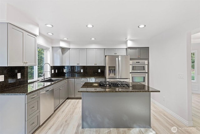 11511 188th St SE, Snohomish, WA 98296 - kitchen with appliances with stainless steel finishes, dark stone countertops, light wood finished floors, gray cabinets, and decorative backsplash