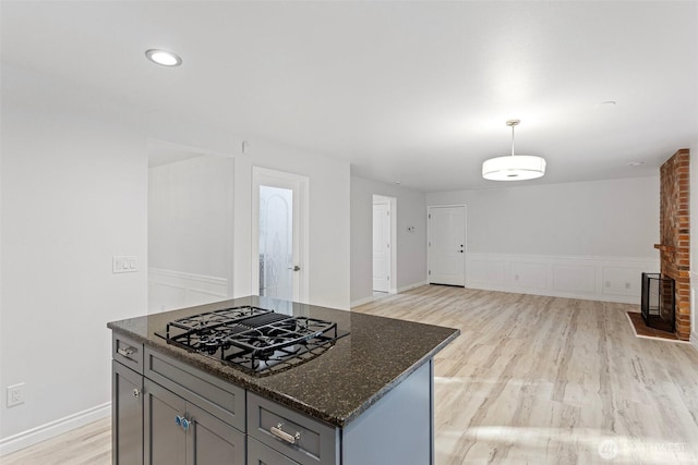 11511 188th St SE, Snohomish, WA 98296 - kitchen featuring black gas cooktop, light wood finished floors, dark stone countertops, gray cabinets, and decorative light fixtures