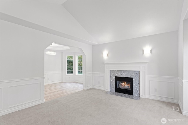 11511 188th St SE, Snohomish, WA 98296 - unfurnished living room with lofted ceiling, a decorative wall, a wainscoted wall, carpet floors, and a high end fireplace