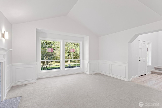 11511 188th St SE, Snohomish, WA 98296 - unfurnished living room with carpet floors, lofted ceiling, wainscoting, a decorative wall, and arched walkways