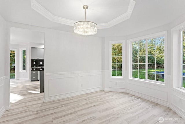 11511 188th St SE, Snohomish, WA 98296 - unfurnished dining area featuring a decorative wall, light wood-type flooring, a chandelier, ornamental molding, and a tray ceiling