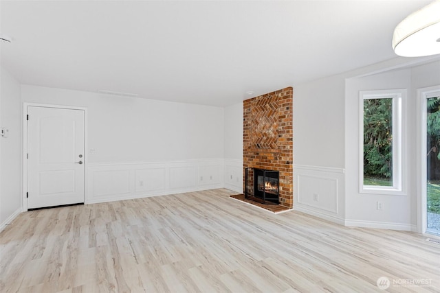 11511 188th St SE, Snohomish, WA 98296 - unfurnished living room with light wood-type flooring, healthy amount of natural light, a fireplace, a wainscoted wall, and a decorative wall