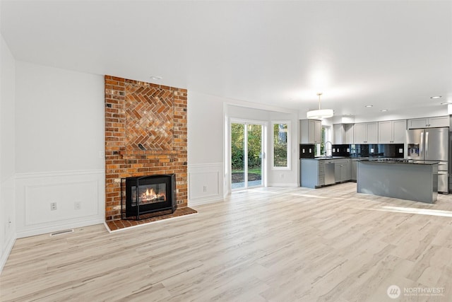 11511 188th St SE, Snohomish, WA 98296 - unfurnished living room featuring light wood-type flooring, a decorative wall, a fireplace, a wainscoted wall, and recessed lighting