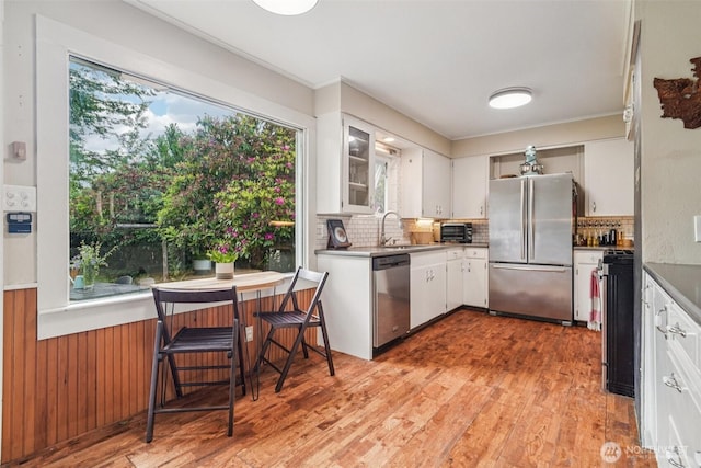 1209 Yew St, Bellingham, WA 98229 - kitchen featuring stainless steel appliances, light wood-style floors, tasteful backsplash, white cabinets, and ornamental molding