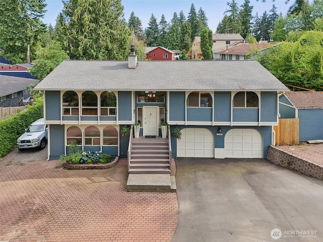 17837 Ashworth Ave N, Shoreline, WA 98133 - bi-level home featuring an attached garage, a chimney, a shingled roof, stucco siding, and asphalt driveway