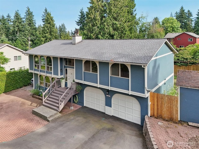 17837 Ashworth Ave N, Shoreline, WA 98133 - bi-level home with asphalt driveway, a chimney, a garage, a shingled roof, and stucco siding
