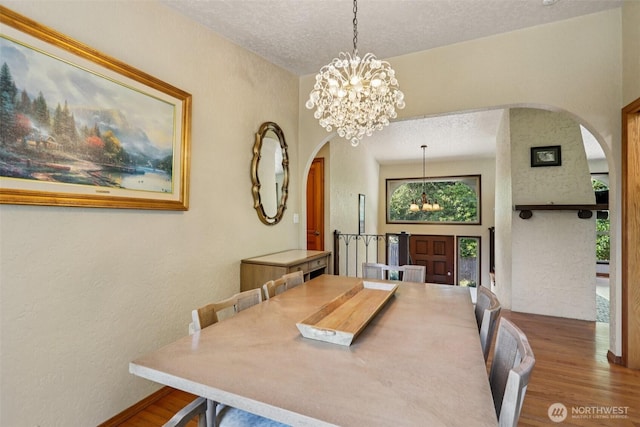 17837 Ashworth Ave N, Shoreline, WA 98133 - dining space featuring arched walkways, wood finished floors, a chandelier, a textured wall, and a textured ceiling