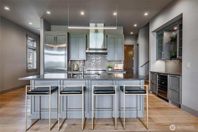 9424 Turnstone Ln Unit 29, Blaine, WA 98230 - kitchen with stainless steel built in fridge, wall chimney range hood, beverage cooler, dark countertops, and backsplash