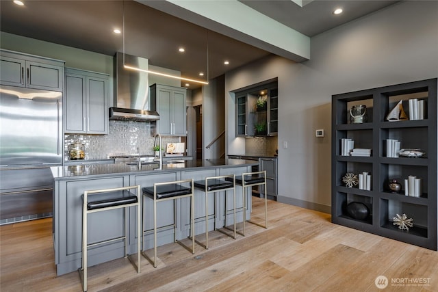 9424 Turnstone Ln Unit 29, Blaine, WA 98230 - kitchen with wall chimney range hood, built in refrigerator, a kitchen bar, light wood-style floors, and recessed lighting