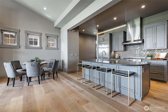 9424 Turnstone Ln Unit 29, Blaine, WA 98230 - kitchen featuring wall chimney exhaust hood, dark countertops, a kitchen breakfast bar, tasteful backsplash, and an island with sink