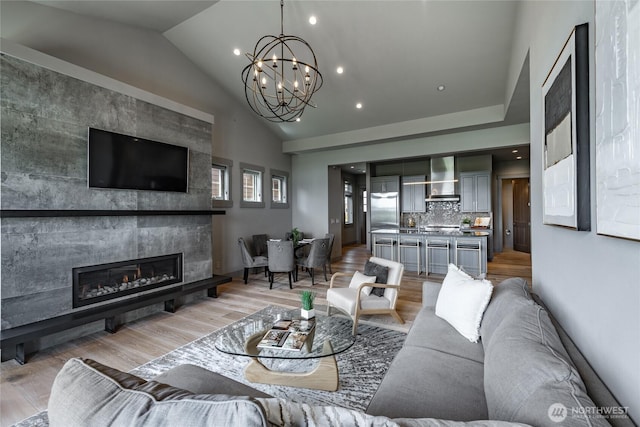 9424 Turnstone Ln Unit 29, Blaine, WA 98230 - living area featuring vaulted ceiling, a chandelier, a glass covered fireplace, light wood-style floors, and recessed lighting