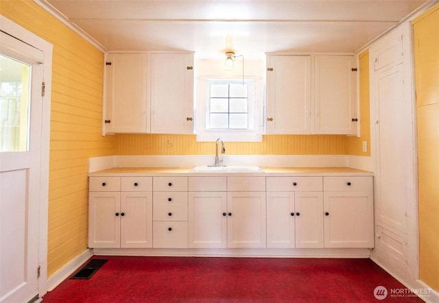 835 J St, Port Townsend, WA 98368 - kitchen with white cabinets, light countertops, wood walls, and dark carpet