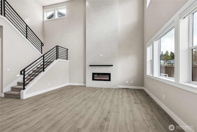 14449 133rd Pl NE, Woodinville, WA 98072 - unfurnished living room with wood finished floors, a high ceiling, stairs, and a large fireplace
