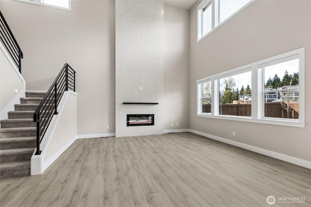 14449 133rd Pl NE, Woodinville, WA 98072 - unfurnished living room with a high ceiling, wood finished floors, stairs, and a large fireplace