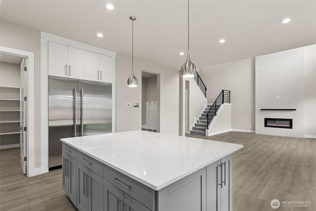 14449 133rd Pl NE, Woodinville, WA 98072 - kitchen featuring built in refrigerator, gray cabinets, light wood finished floors, a center island, and light stone counters