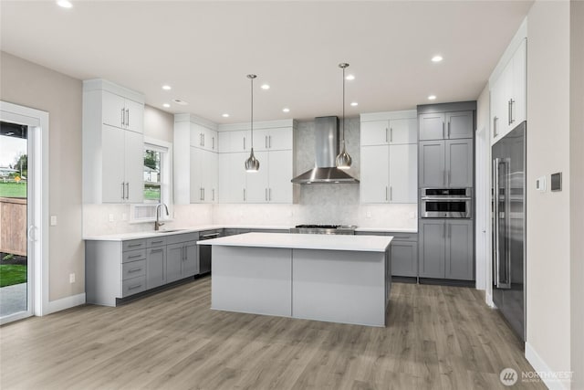14449 133rd Pl NE, Woodinville, WA 98072 - kitchen featuring wall chimney exhaust hood, stainless steel appliances, gray cabinetry, light wood-style floors, and a kitchen island
