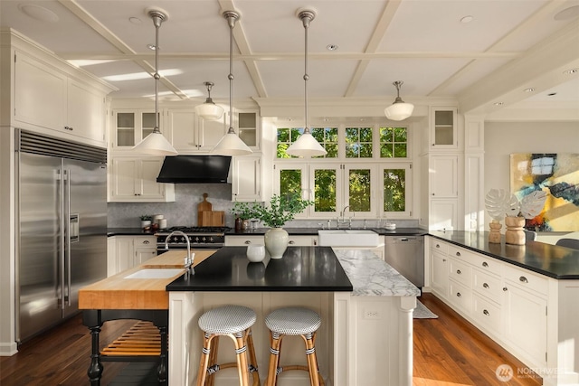 2665 Evergreen Point Rd NE, Medina, WA 98039 - kitchen with appliances with stainless steel finishes, ventilation hood, a center island with sink, coffered ceiling, and dark wood-style floors