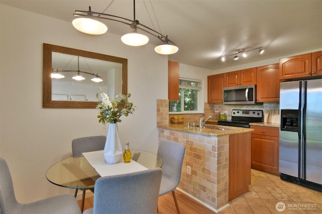 13021 SE 38th St Unit J8, Bellevue, WA 98006 - kitchen featuring appliances with stainless steel finishes, decorative backsplash, light stone counters, a peninsula, and pendant lighting