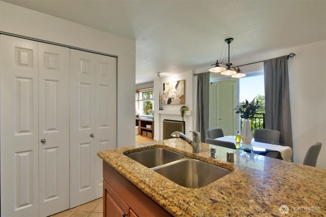 13021 SE 38th St Unit J8, Bellevue, WA 98006 - kitchen featuring light tile patterned floors, light stone counters, hanging light fixtures, a fireplace, and brown cabinetry