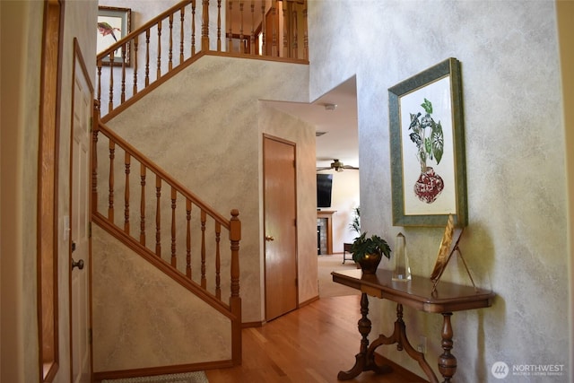 1017 Kelley Ridge Ct, Bellingham, WA 98229 - staircase with a high ceiling, ceiling fan, wood finished floors, and a glass covered fireplace