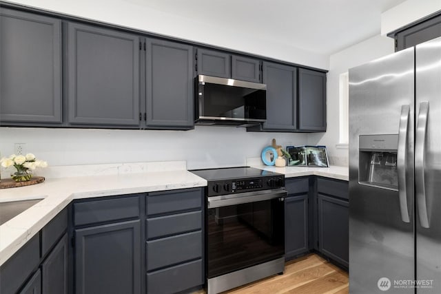 9641 NE 121st Ln, Kirkland, WA 98034 - kitchen featuring stainless steel appliances, light stone counters, light wood finished floors, and gray cabinetry