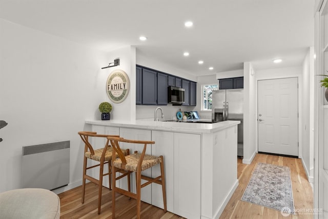 9641 NE 121st Ln, Kirkland, WA 98034 - kitchen with appliances with stainless steel finishes, a peninsula, light wood-style flooring, recessed lighting, and a kitchen bar