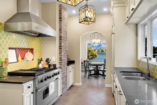 19453 Military Rd S, Seatac, WA 98188 - kitchen with wall chimney exhaust hood, high end stainless steel range oven, a chandelier, dark countertops, and light tile patterned floors