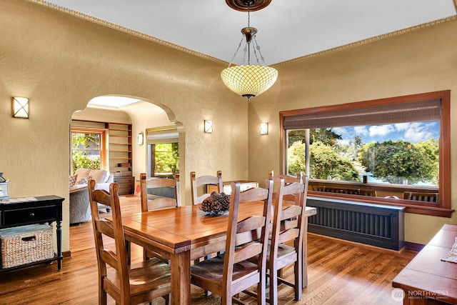 19453 Military Rd S, Seatac, WA 98188 - dining space featuring a textured wall, arched walkways, wood finished floors, and crown molding