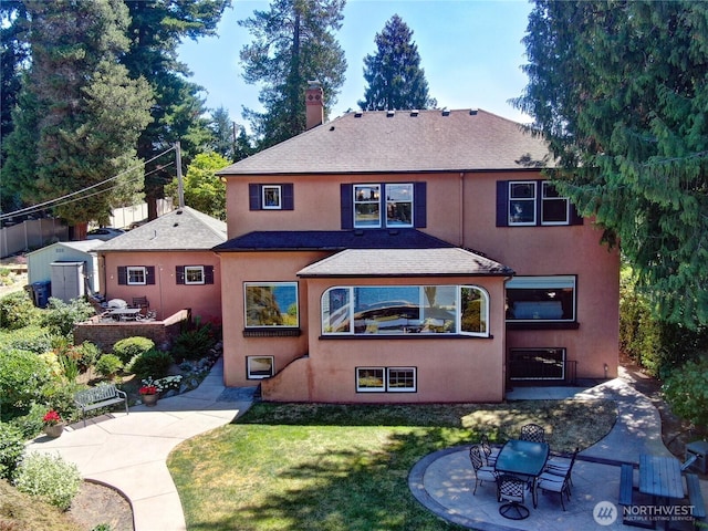 19453 Military Rd S, Seatac, WA 98188 - back of property featuring stucco siding, a shingled roof, a chimney, a lawn, and a patio area