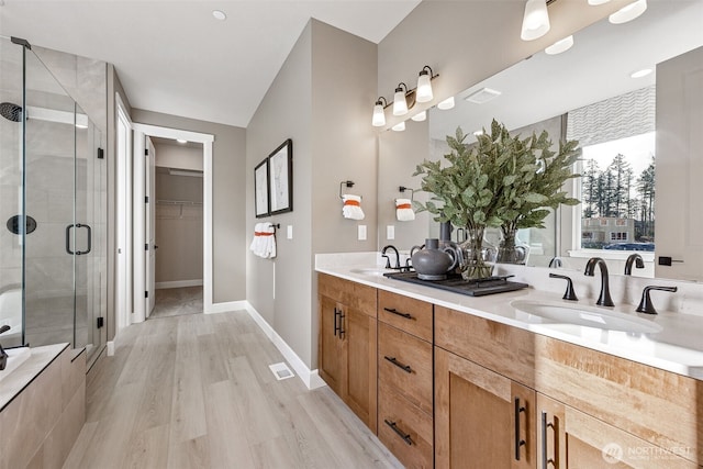 18019 139th Pl E Unit 19, Puyallup, WA 98374 - bathroom featuring a stall shower, double vanity, a spacious closet, and wood finished floors
