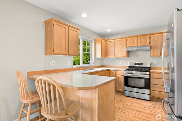 6209 Lincoln Dr, Ferndale, WA 98248 - kitchen featuring appliances with stainless steel finishes, a peninsula, light wood-style flooring, light countertops, and under cabinet range hood
