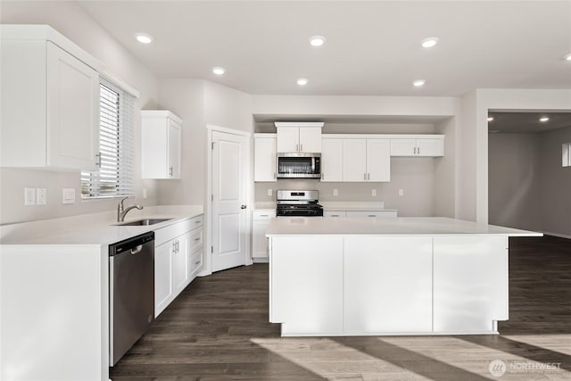 3913 23rd Ave NE Unit 97, Olympia, WA 98516 - kitchen with appliances with stainless steel finishes, white cabinets, dark wood finished floors, a kitchen island, and light countertops