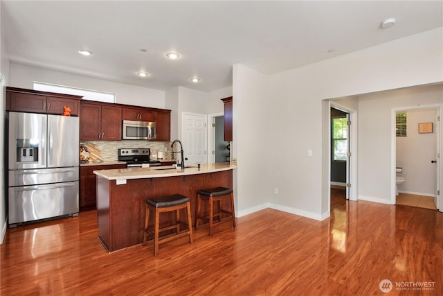 2025 Palisade Blvd, Dupont, WA 98327 - kitchen with stainless steel appliances, a breakfast bar area, dark wood-type flooring, light countertops, and decorative backsplash