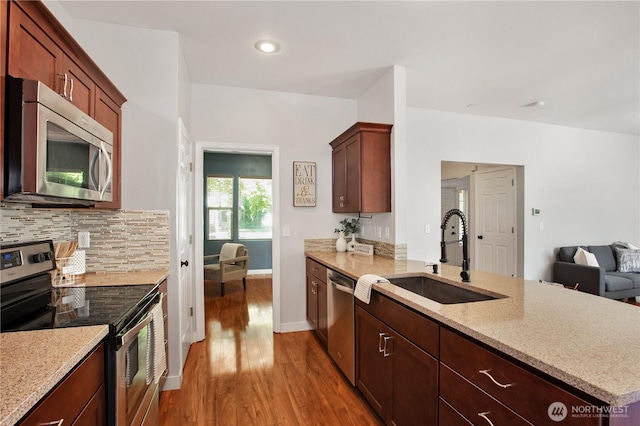 2025 Palisade Blvd, Dupont, WA 98327 - kitchen featuring stainless steel appliances, wood finished floors, a peninsula, backsplash, and light stone counters
