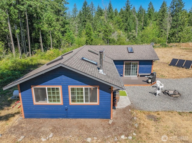 19002 Sorenson Rd SE, Yelm, WA 98597 - rear view of property with a shingled roof, a wooded view, and solar panels